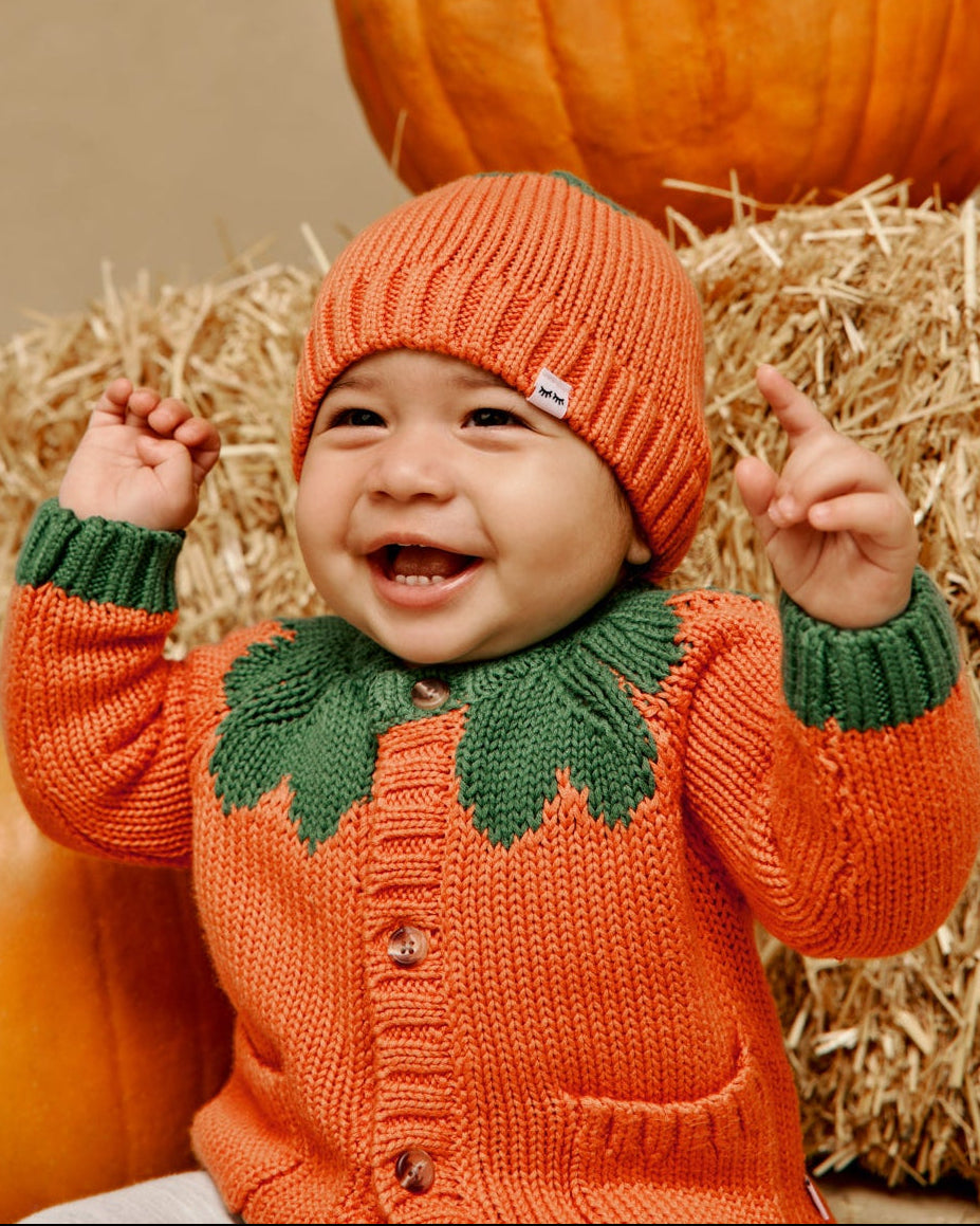 Happy baby wearing a pumpkin knit cardigan fall sweater for babies and toddlers