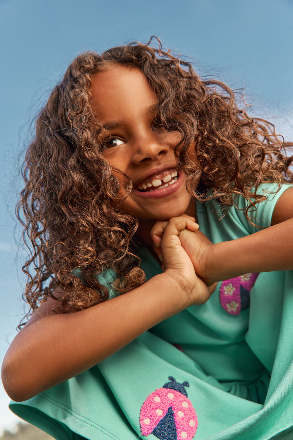 Close up of child wearing the Garden Party Pocket Dress with a sky blue background