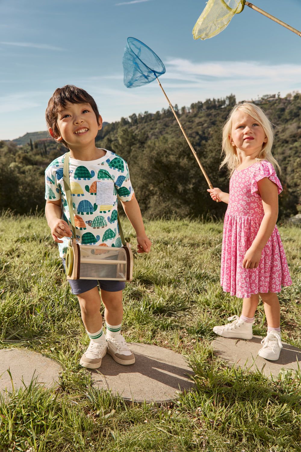 Two children wearing Play styles from the Spring Capsule with a grassy background