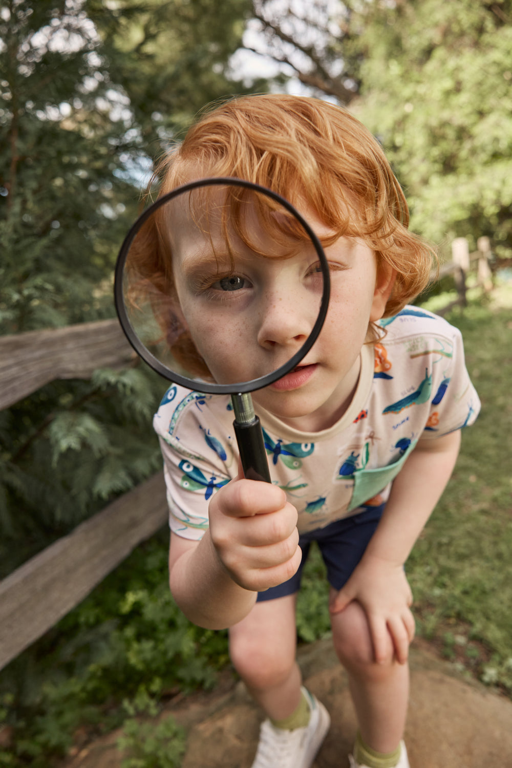 Boy looking through a magnifying glass wearing the Nature Notes Relaxed Pocket Tee