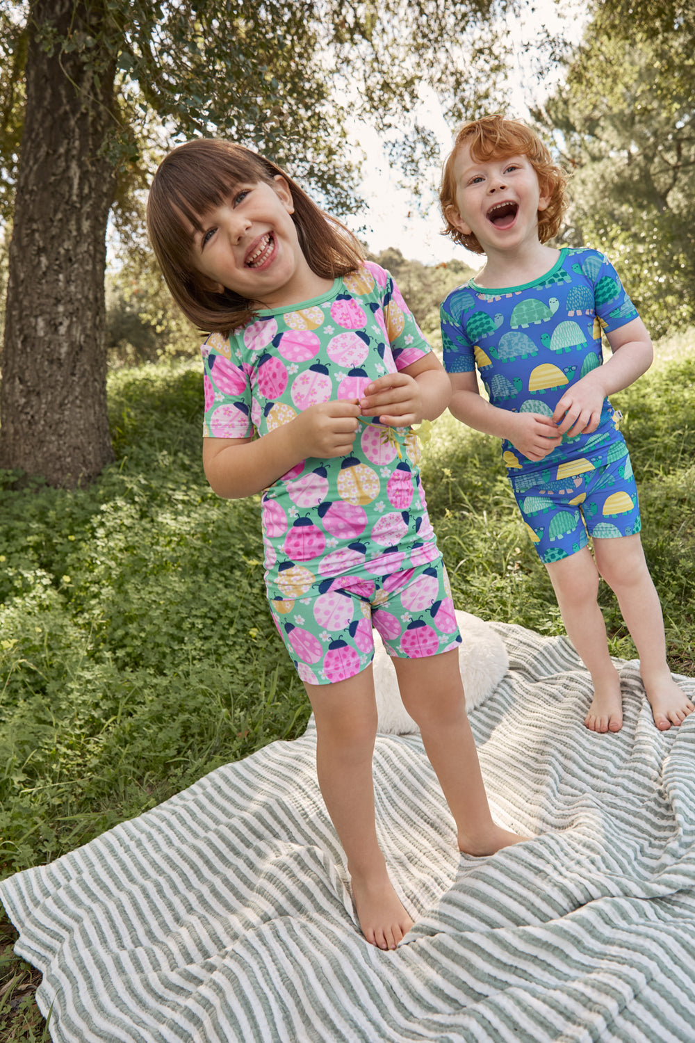 Two children wearing ladybug and turtle printed pajamas