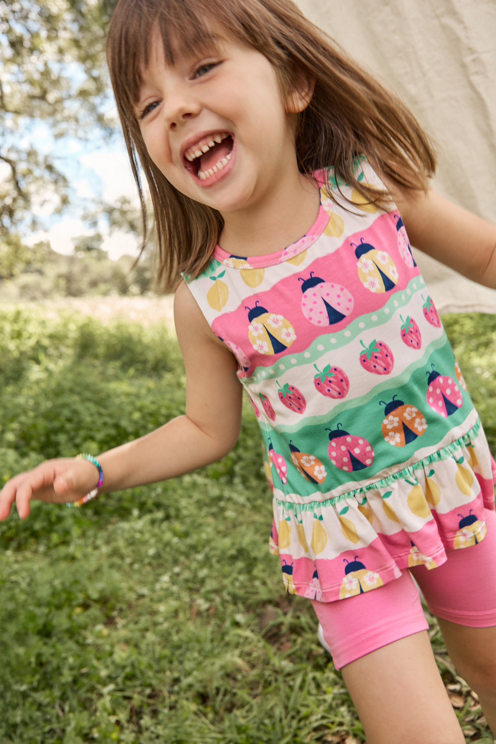 Girl wearing the Ladybug Lane Peplum Tank with pink shorts