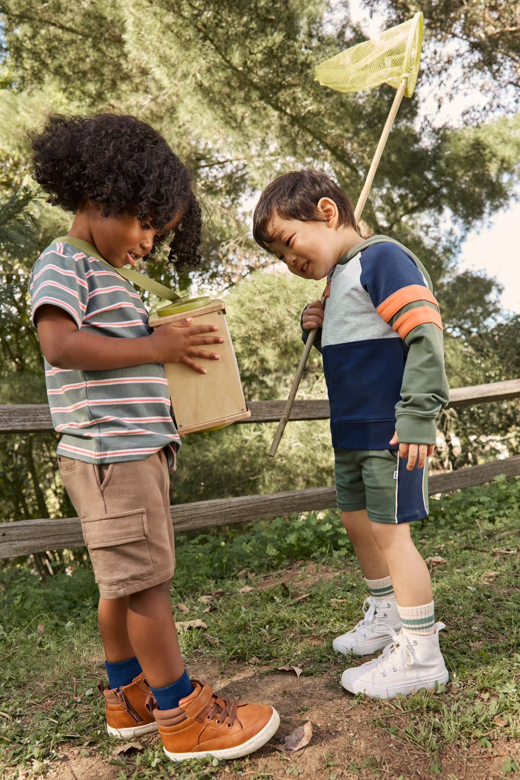 Two children in a wooded area wearing Play styles from the spring capsule