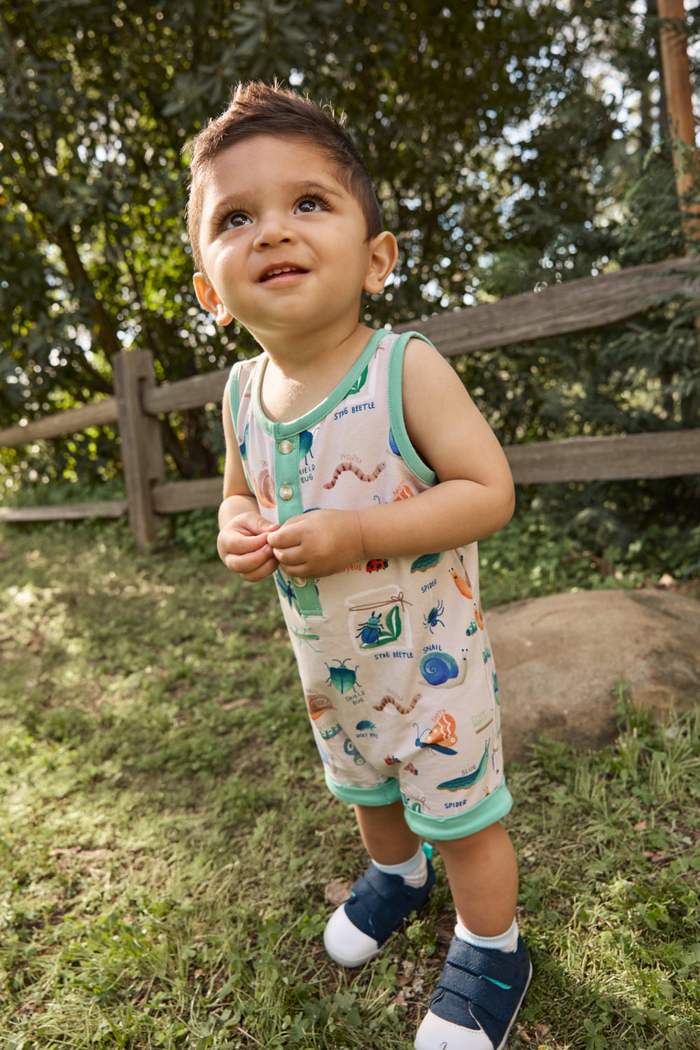 Child wearing the Nature Notes Henley Romper with navy shoes