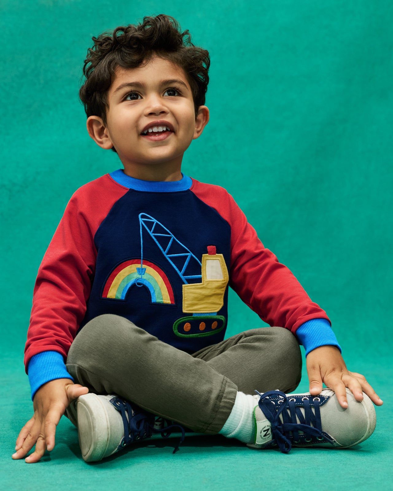 Boy wearing the Rainbow Trucks Crewneck Sweatshirt on a teal background