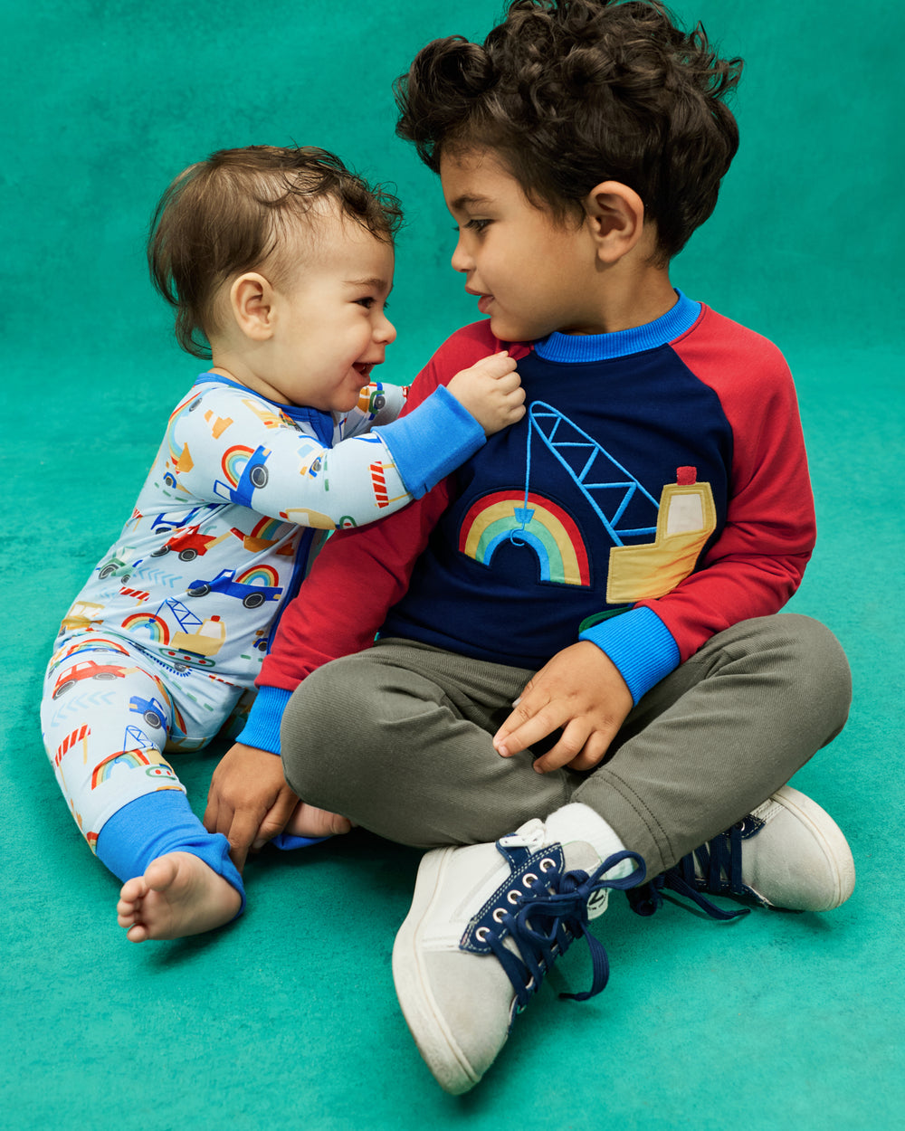 Two children wearing Rainbow Trucks Sleep and Play styles