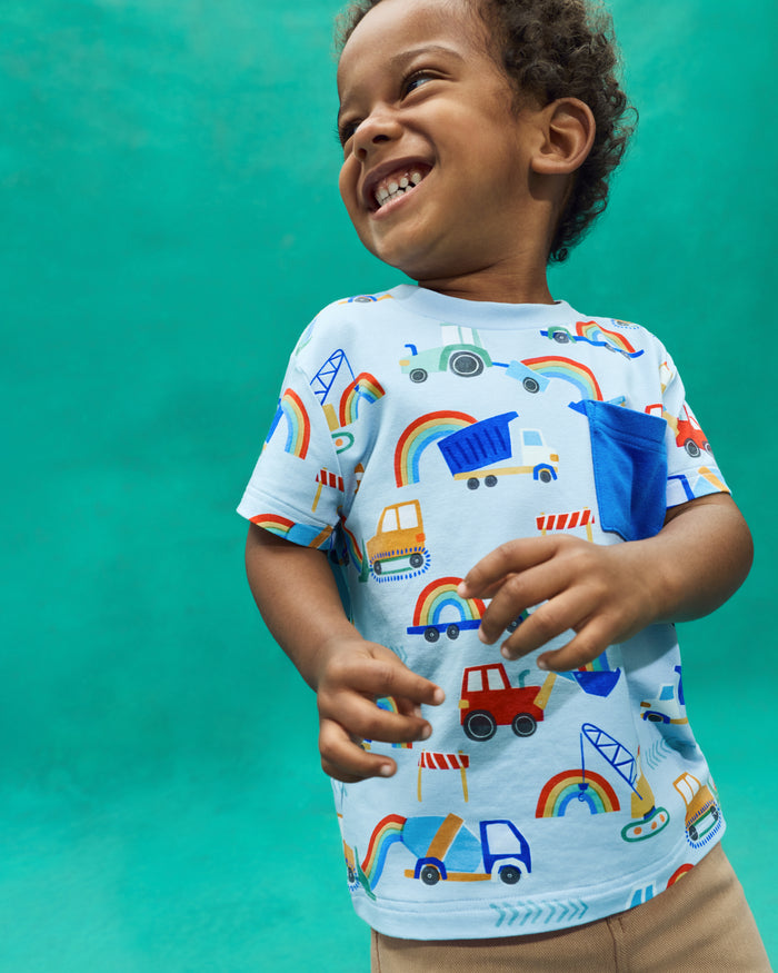 Flat lay of the Rainbow Trucks Relaxed Pocket Tee on a teal back drop
