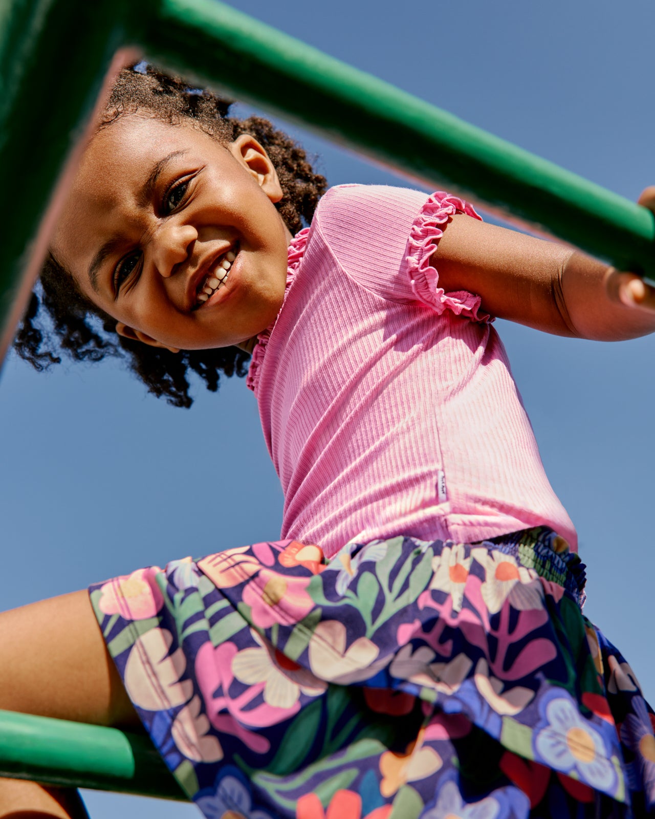 Girl wearing the Wild Garden Tiered Skort with a pink ribbed tee on a playground