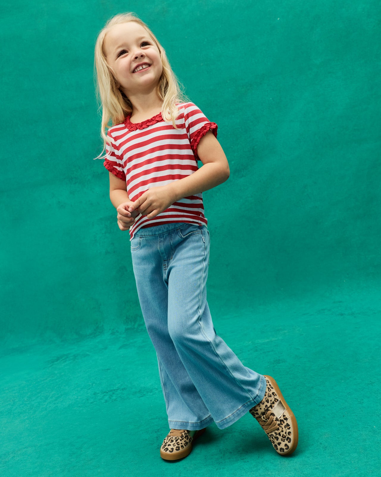 Girl wearing the Red Ember Stripe Ruffle Tee with wide leg denim pants