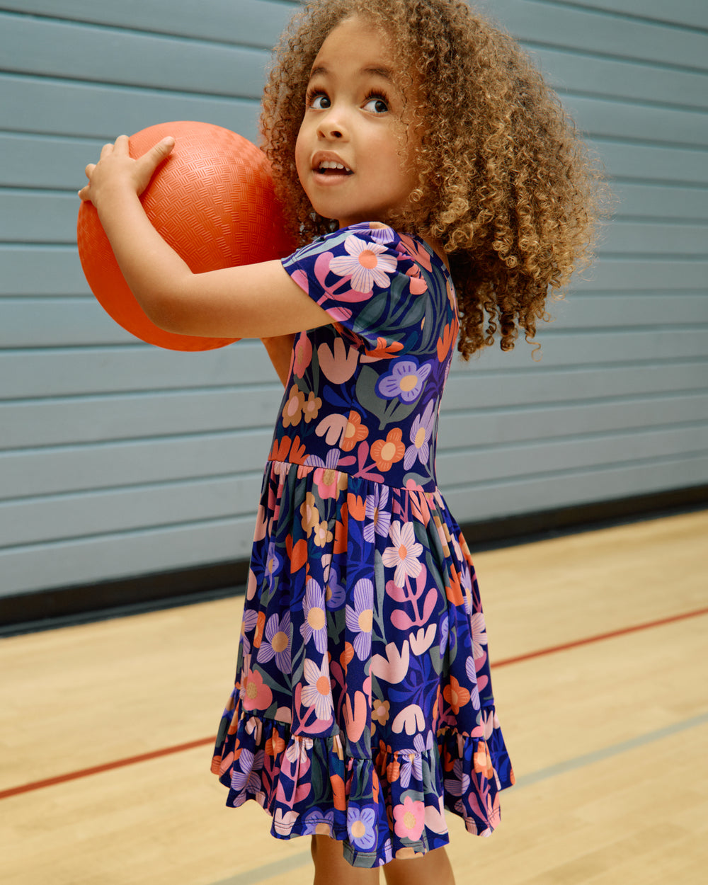 Girl wearing the Wild Garden Ruffle Twirl Dress holding a kickball
