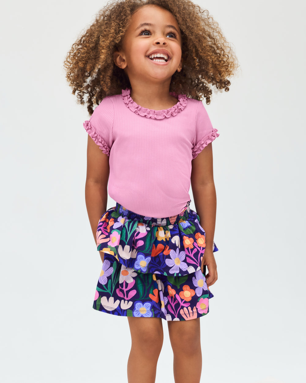 Girl wearing the Blush Orchid Ruffle Tee with a floral skirt