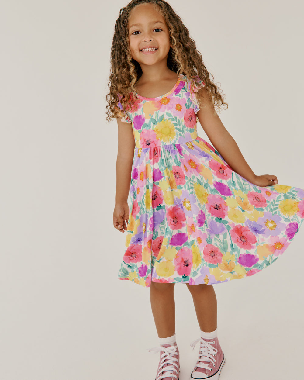 Girl wearing the Watercolor Meadow Flutter Twirl Dress holding out the skirt