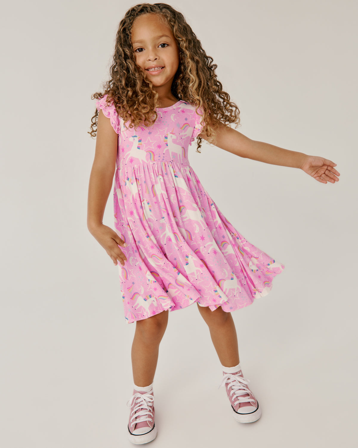 Standing girl wearing the Unicorn Dance Flutter Twirl Dress with pink sneakers