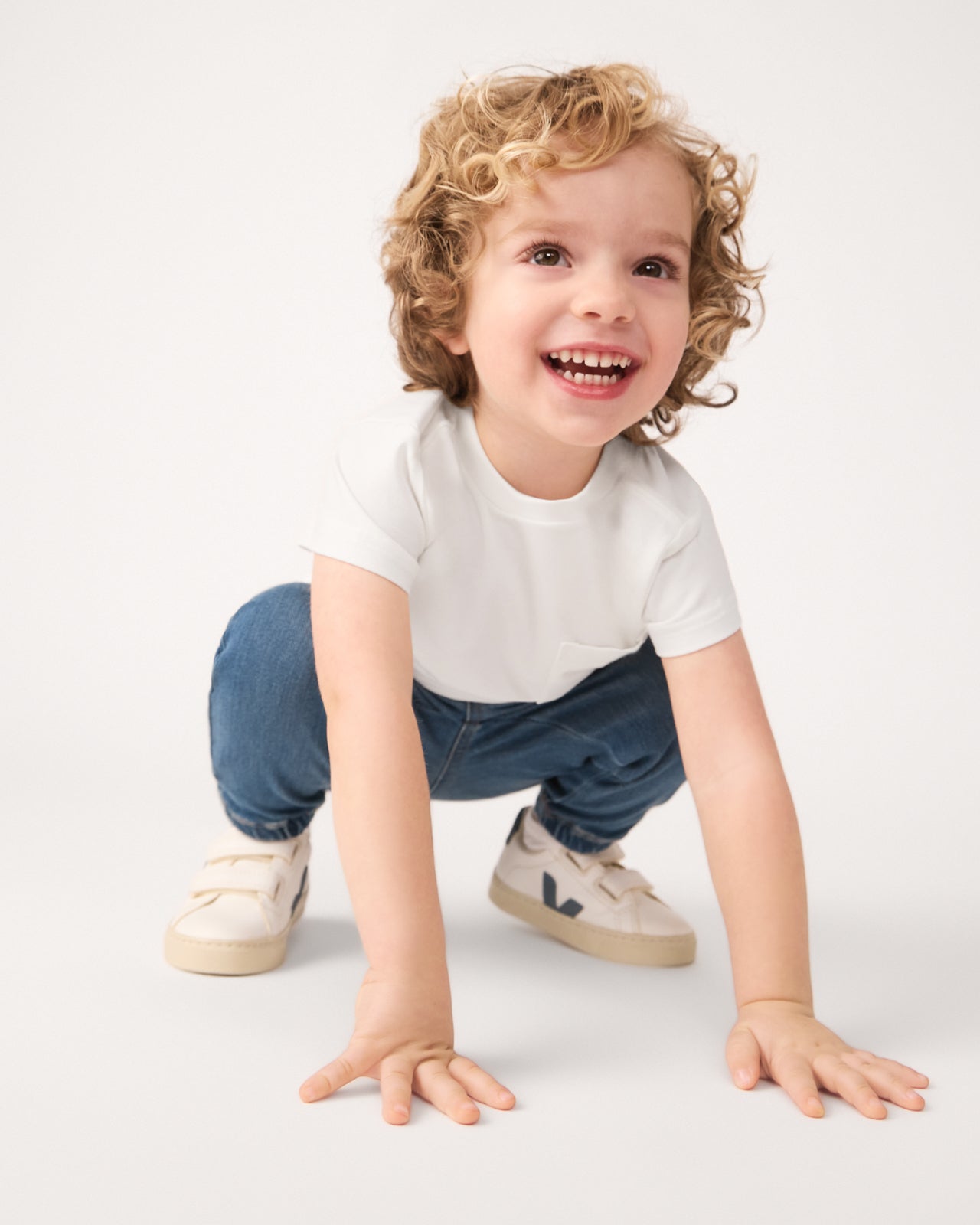 Crouching child wearing the Soft White Short Sleeve Relaxed Pocket Tee 