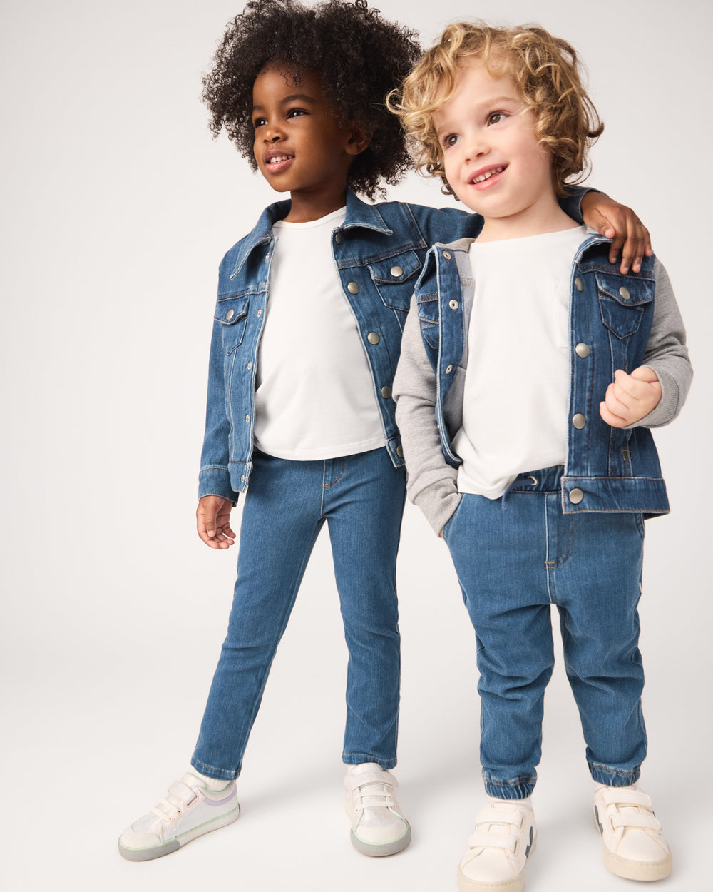 Two children wearing matching midwash blue denim styles