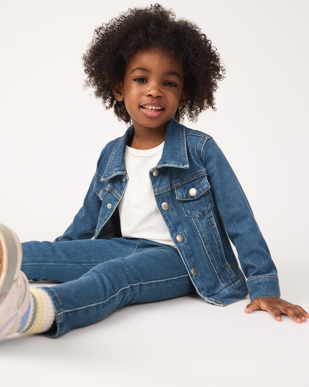 Sitting girl wearing the Midwash Blue Denim Jegging and Jacket