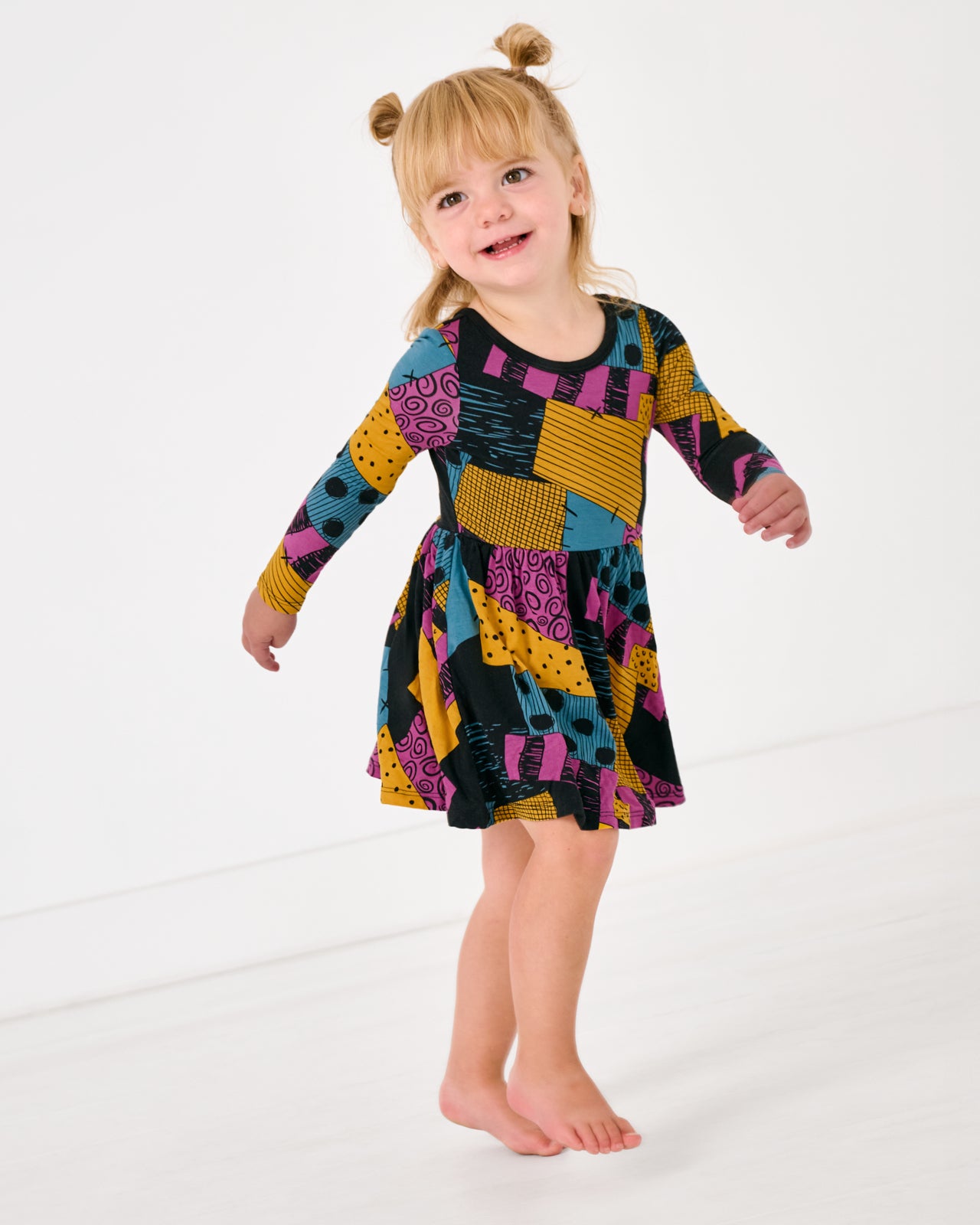 Walking toddler wearing the Disney Sally's Patchwork Twirl Dress with Bodysuit