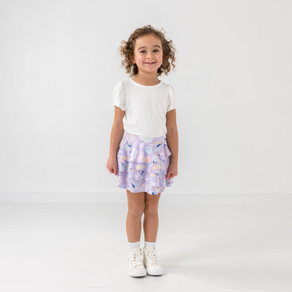 Standing child wearing the Sandy Treasures Ruffle Skort with a white puff sleeve top