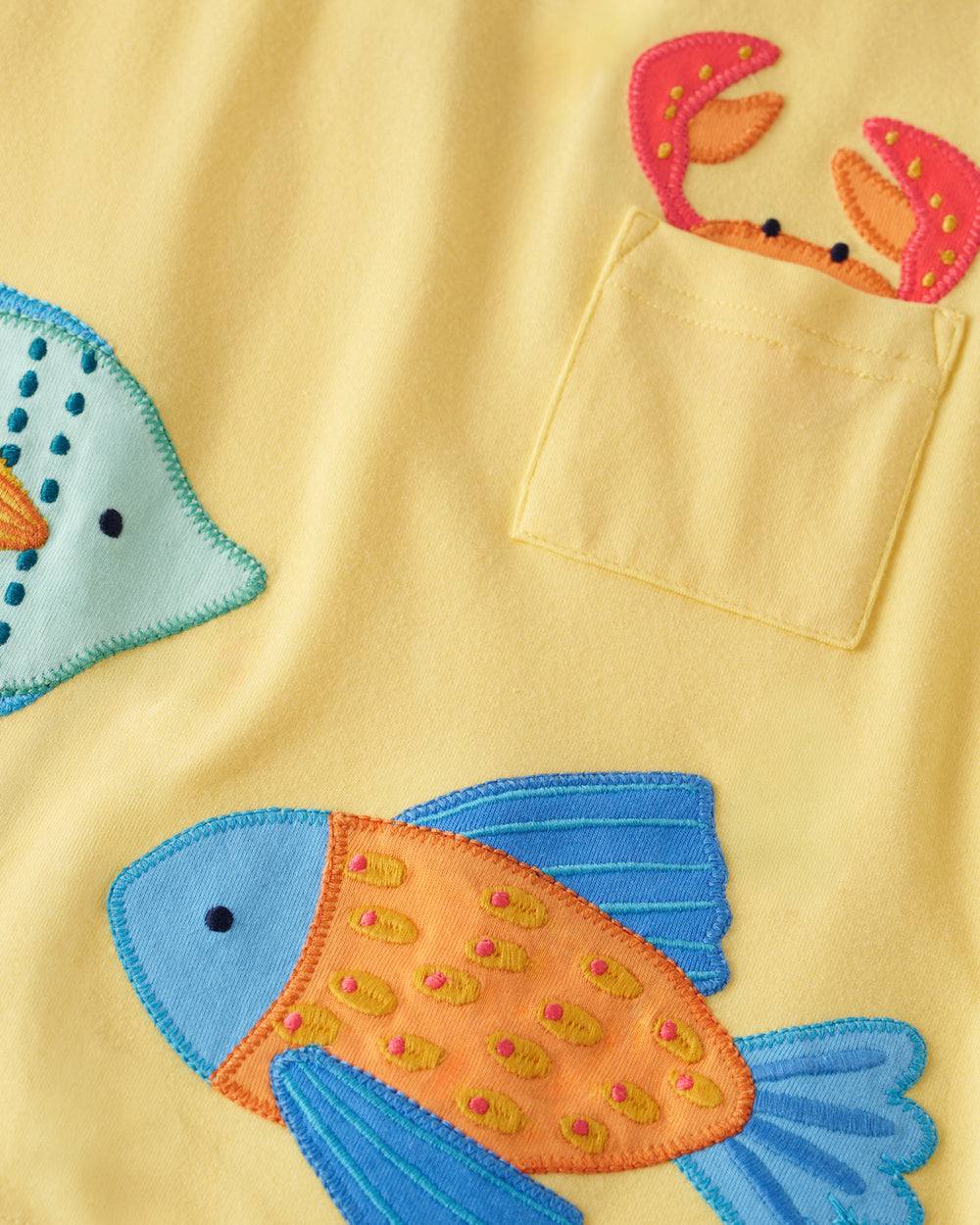 Close up of the embroidered fish details on the School of Friends Relaxed Pocket Tee