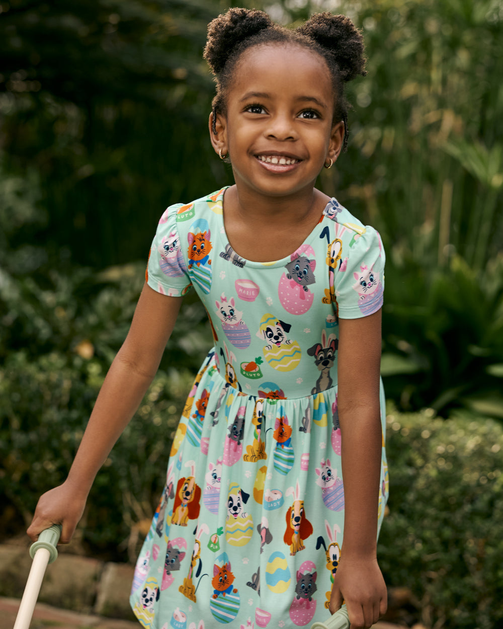 Child wearing the Disney Peekaboo Pets Bow Back Skater Dress with greenery in the background