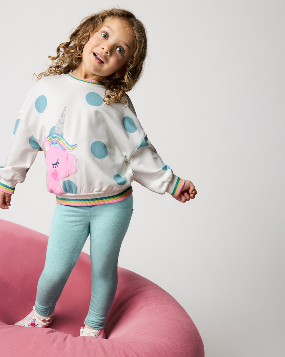 Girl wearing the Unicorn Drop Shoulder Crewneck with teal leggings 