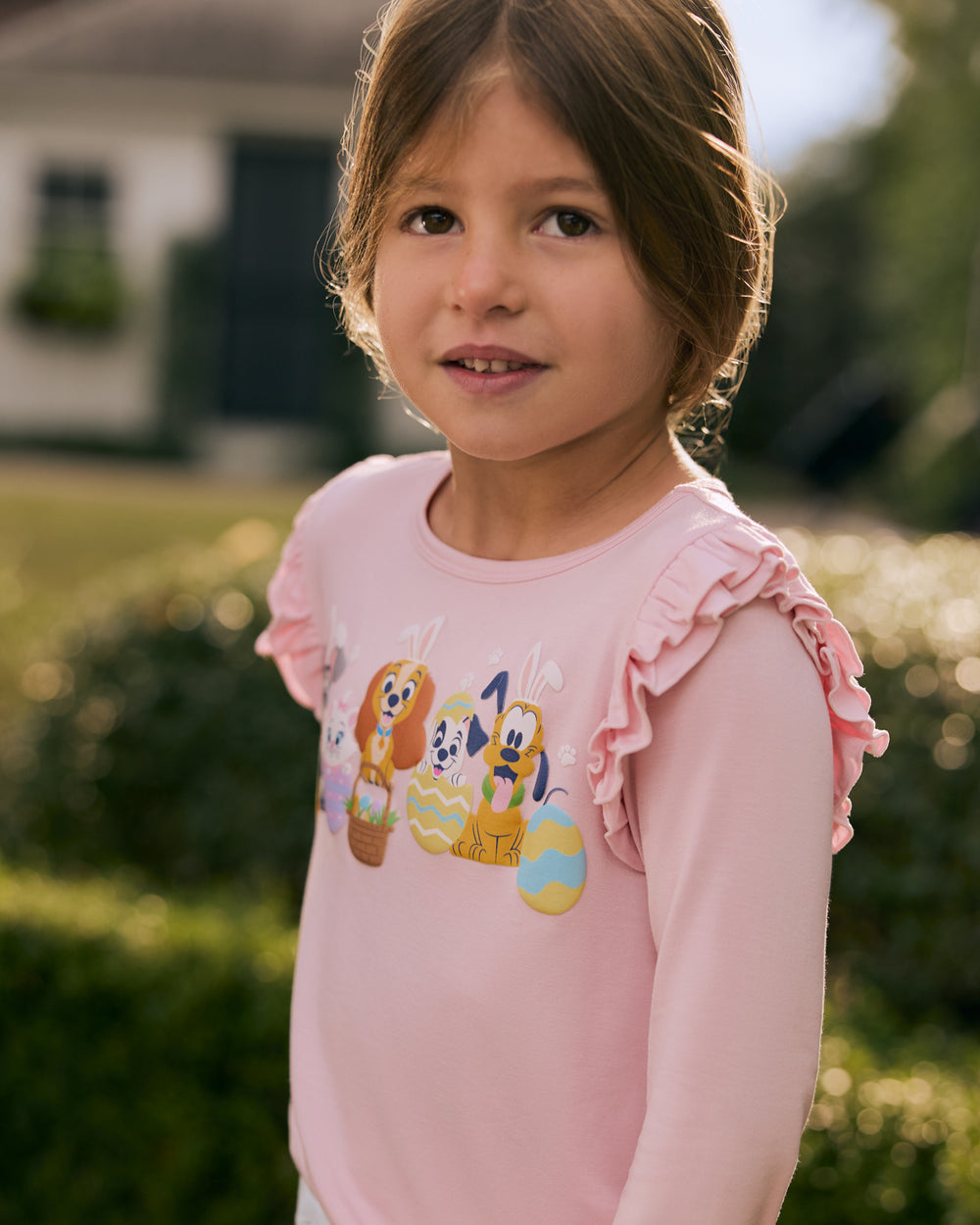 Child wearing the Disney Peekaboo Pets Flutter Tee with a garden in the background