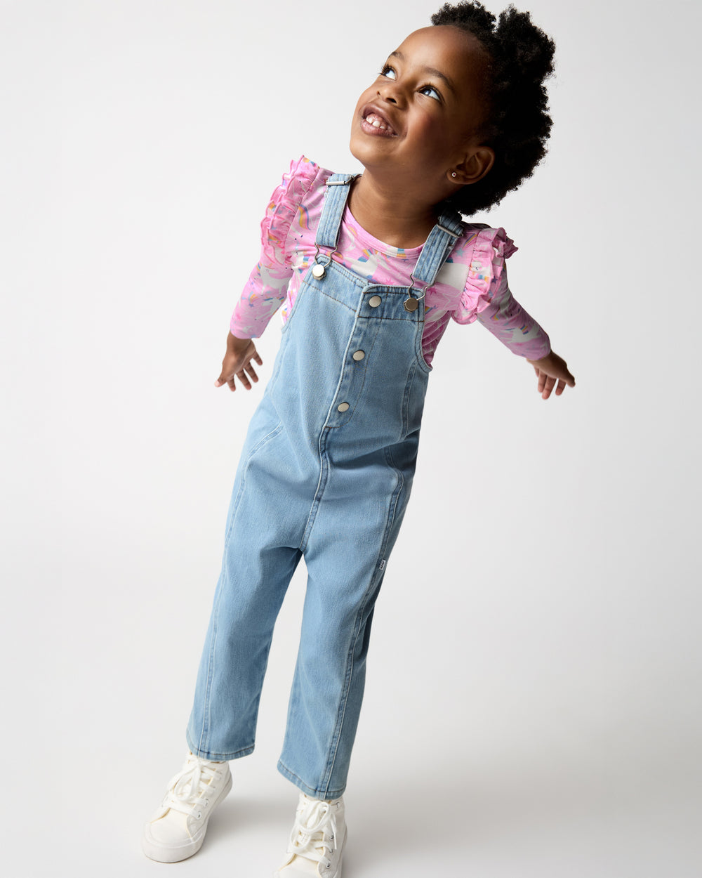 Girl wearing the Light Blue Denim Overall layered over a pink flutter tee