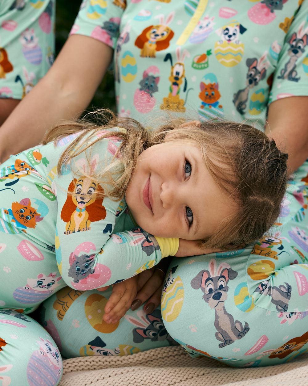 Child wearing the Disney Peekaboo Pets Two-Piece Pajama Set with her mother in the background