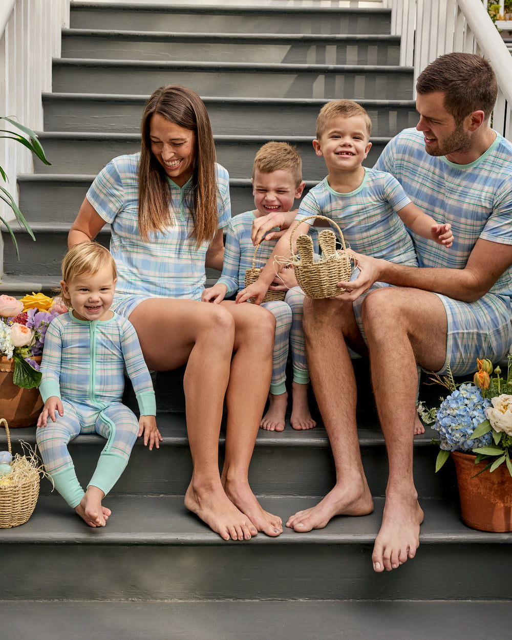 Family of five sitting on steps wearing matching blue and green plaid Easter pajamas