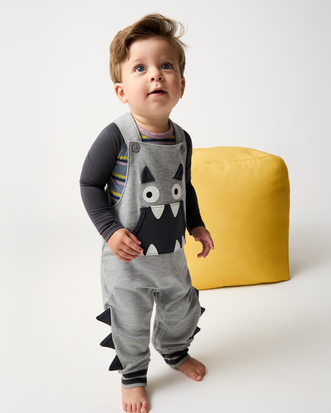 Boy wearing the Monster Overall layered over the Ollie Stripe bodysuit