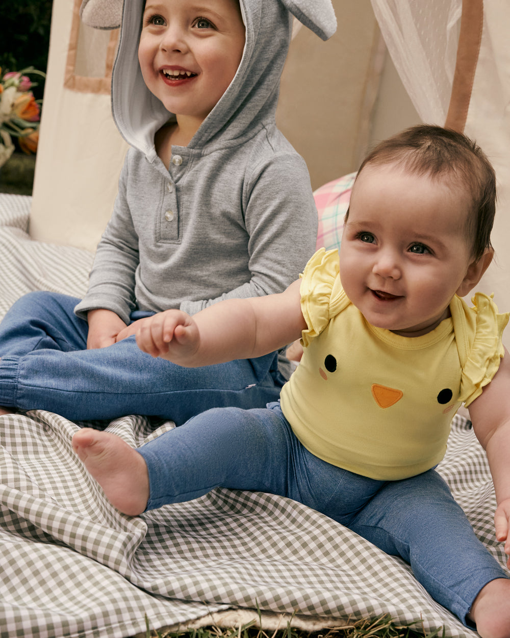 Two children wearing Easter Play styles on a gingham blanket