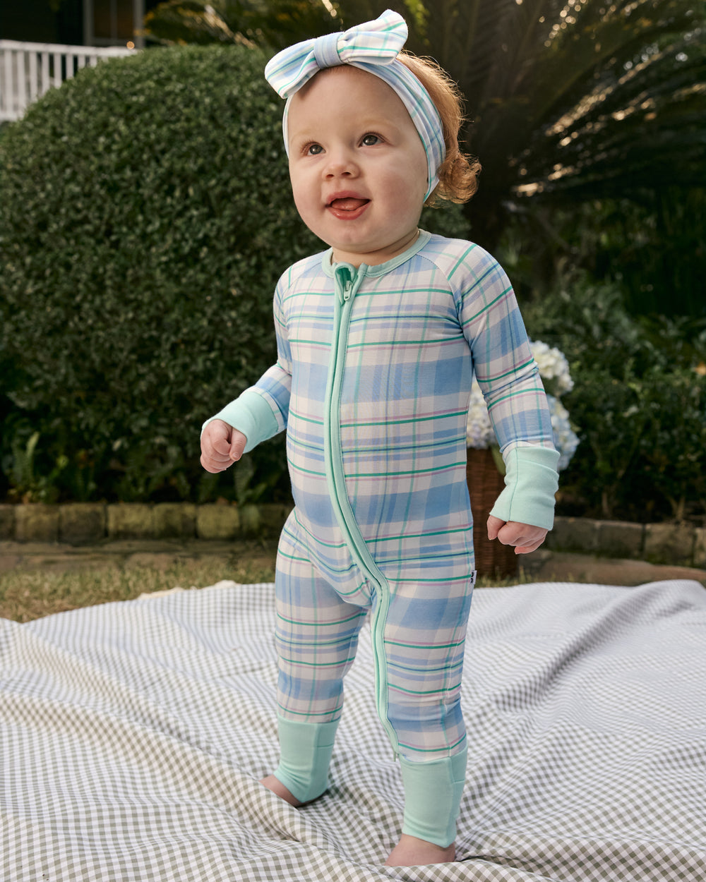 Child standing on a gingham blanket wearing the Springtime Plaid Zippy