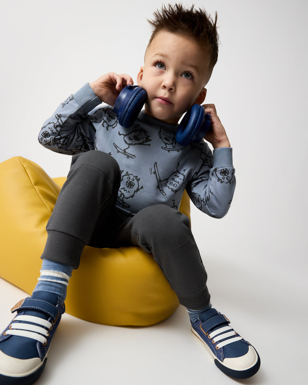 Boy wearing the Monster Moves Crewneck Sweatshirt on a yellow ottomon