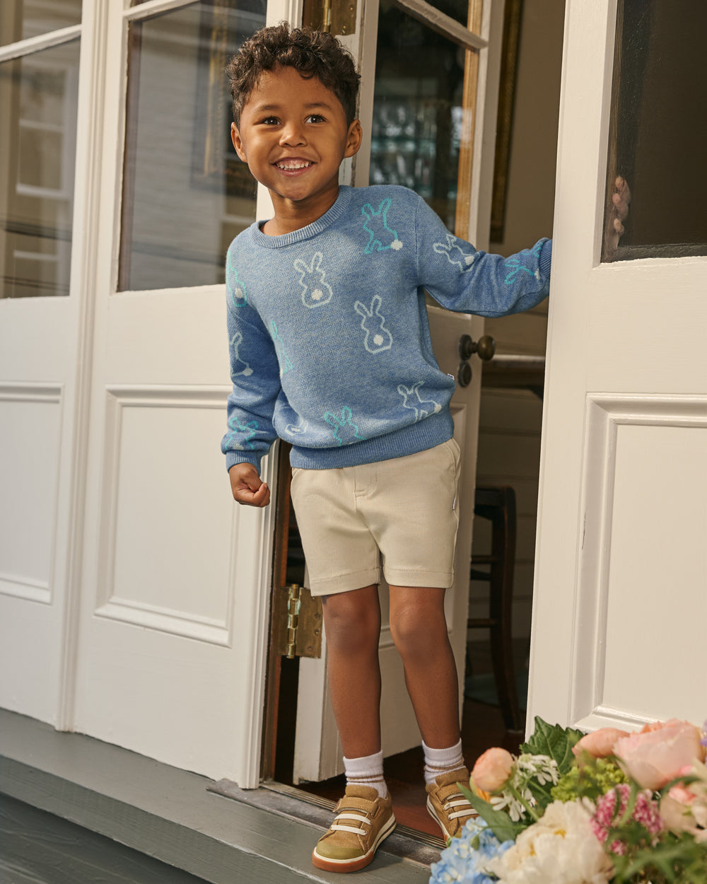 Boy standing in a doorway wearing the Cozy Cottontails Sweater