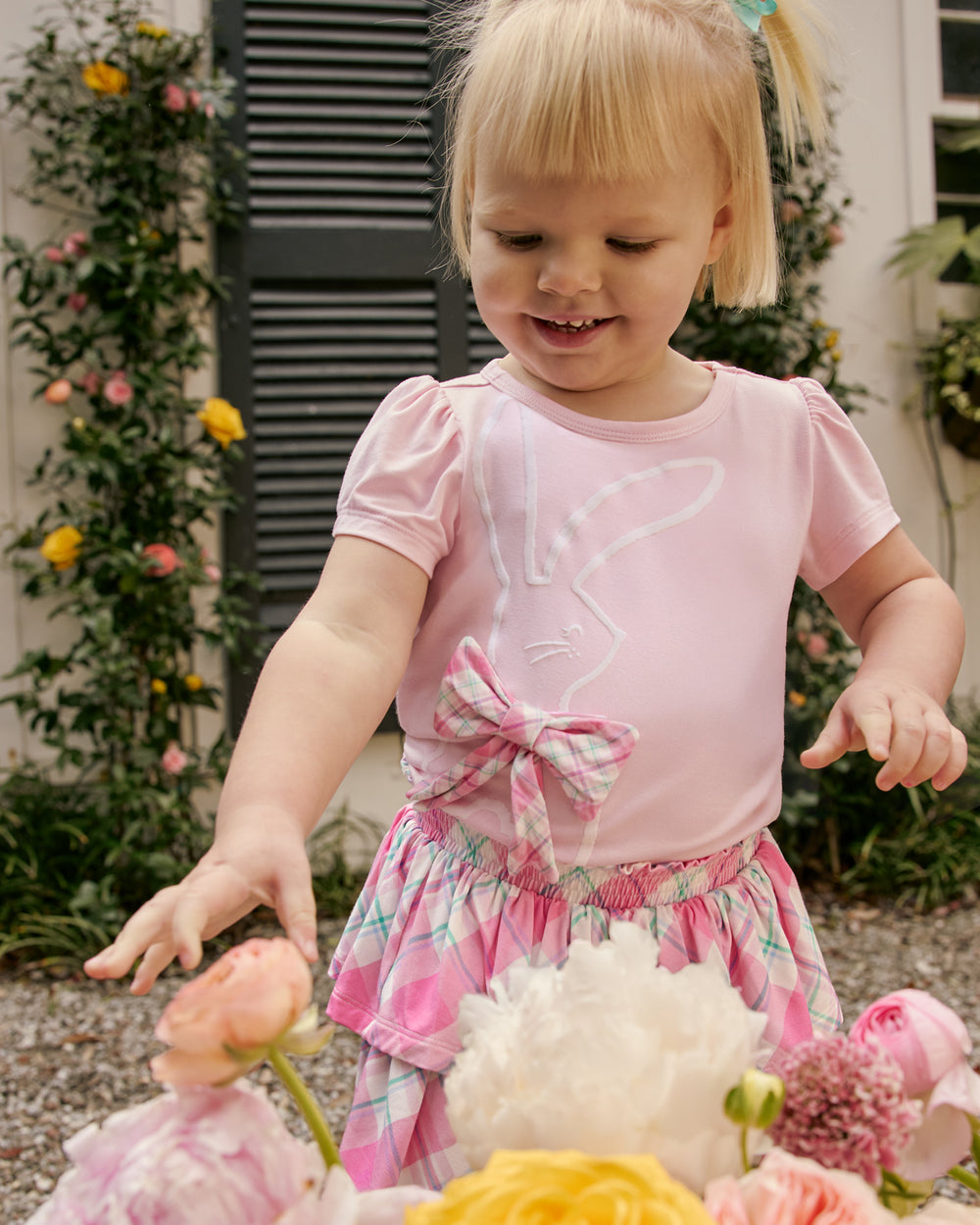 Girl wearing the Flocked Bunny Puff Sleeve Tee reaching for a bouquet of flowers