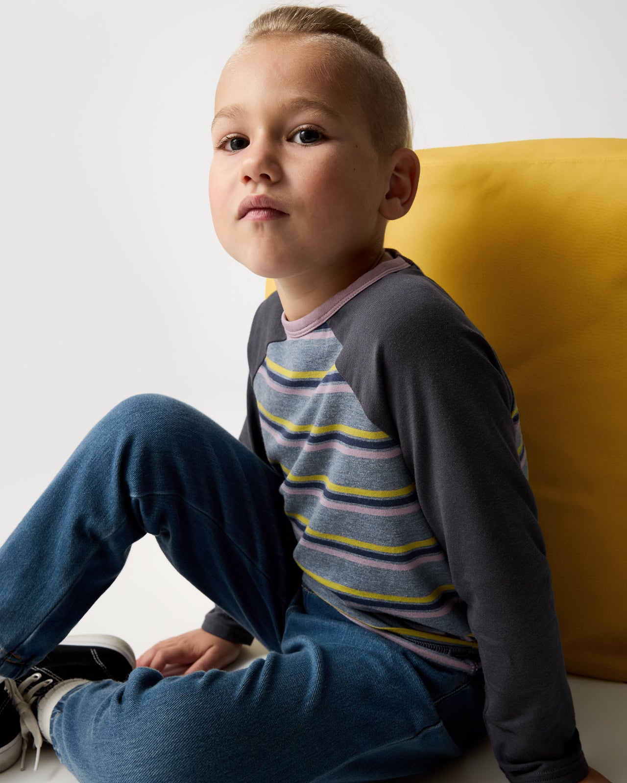Sitting boy wearing the Ollie Stripe Raglan Tee 