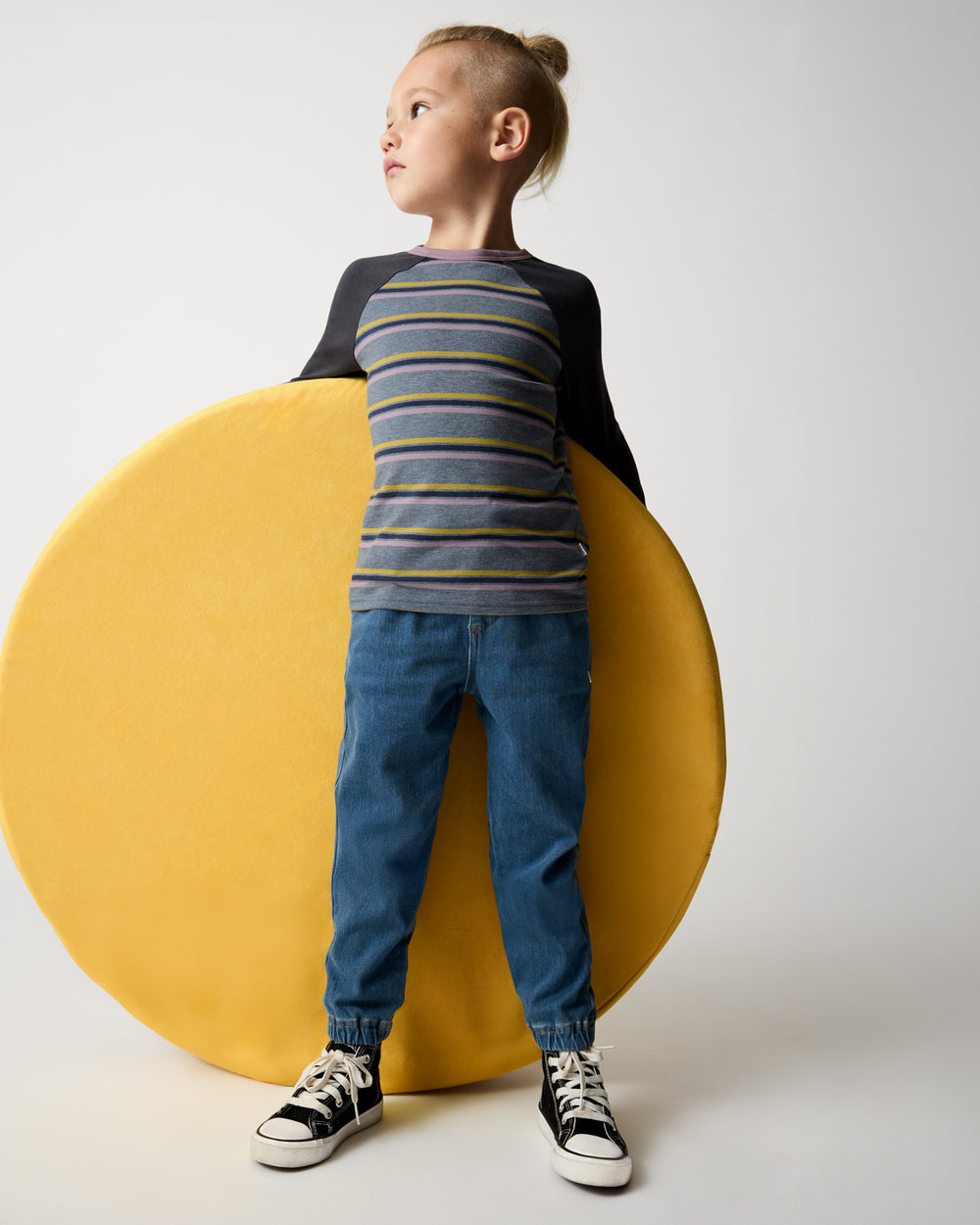 Boy wearing the Ollie Stripe Raglan Tee with denim joggers