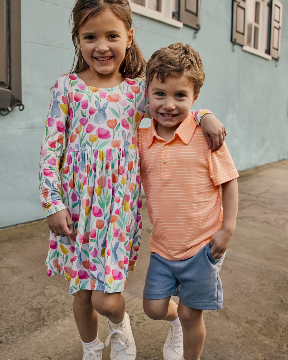 Two children wearing Easter Play styles with a blu building in the background
