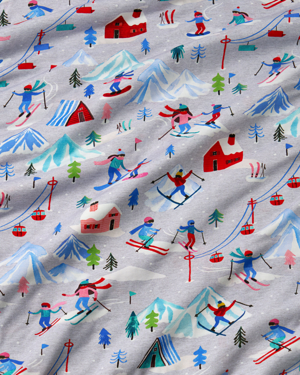 A close-up of a light gray fabric with a colorful ski resort print featuring skiers, snowboarders, mountains, trees, cabins, and ski lifts.