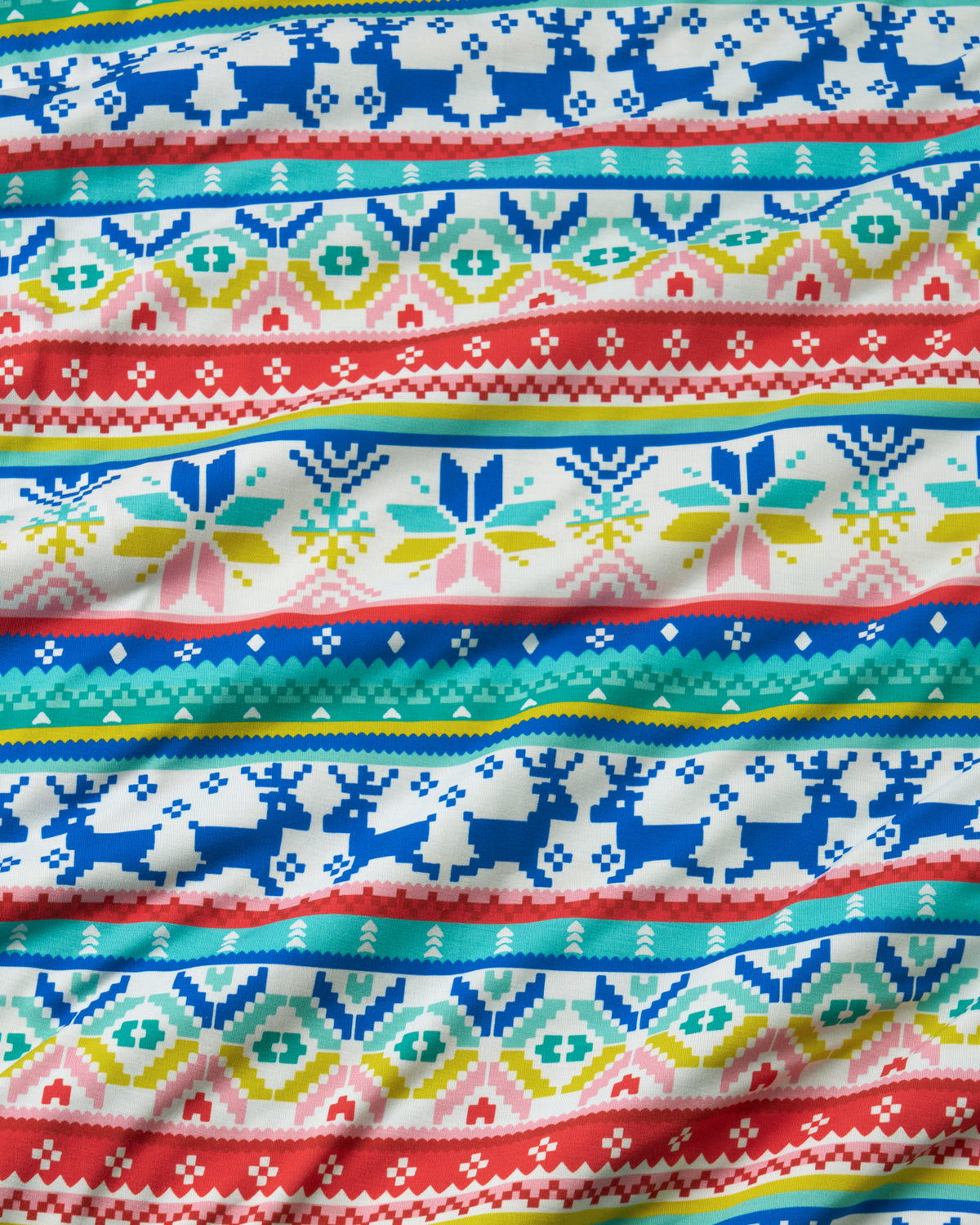 A close-up of a knitted fabric with horizontal Nordic and Fair Isle patterns in red, blue, teal, yellow, and pink on a white background.