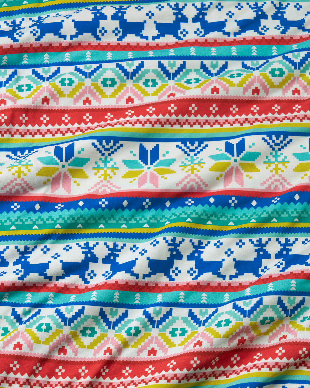 A close-up of a knitted fabric with horizontal Nordic and Fair Isle patterns in red, blue, teal, yellow, and pink on a white background.