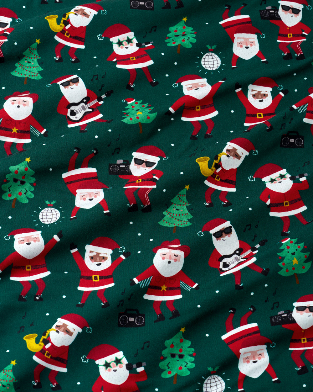 A close-up of a dark green fabric with a repeating pattern of cartoon Santa Claus figures playing music instruments, decorated Christmas trees, and small white musical notes.