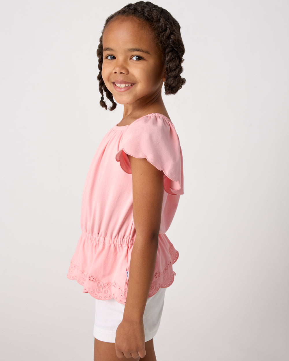 Side view of girl wearing the Soft Coral Puff Sleeve Eyelet Top