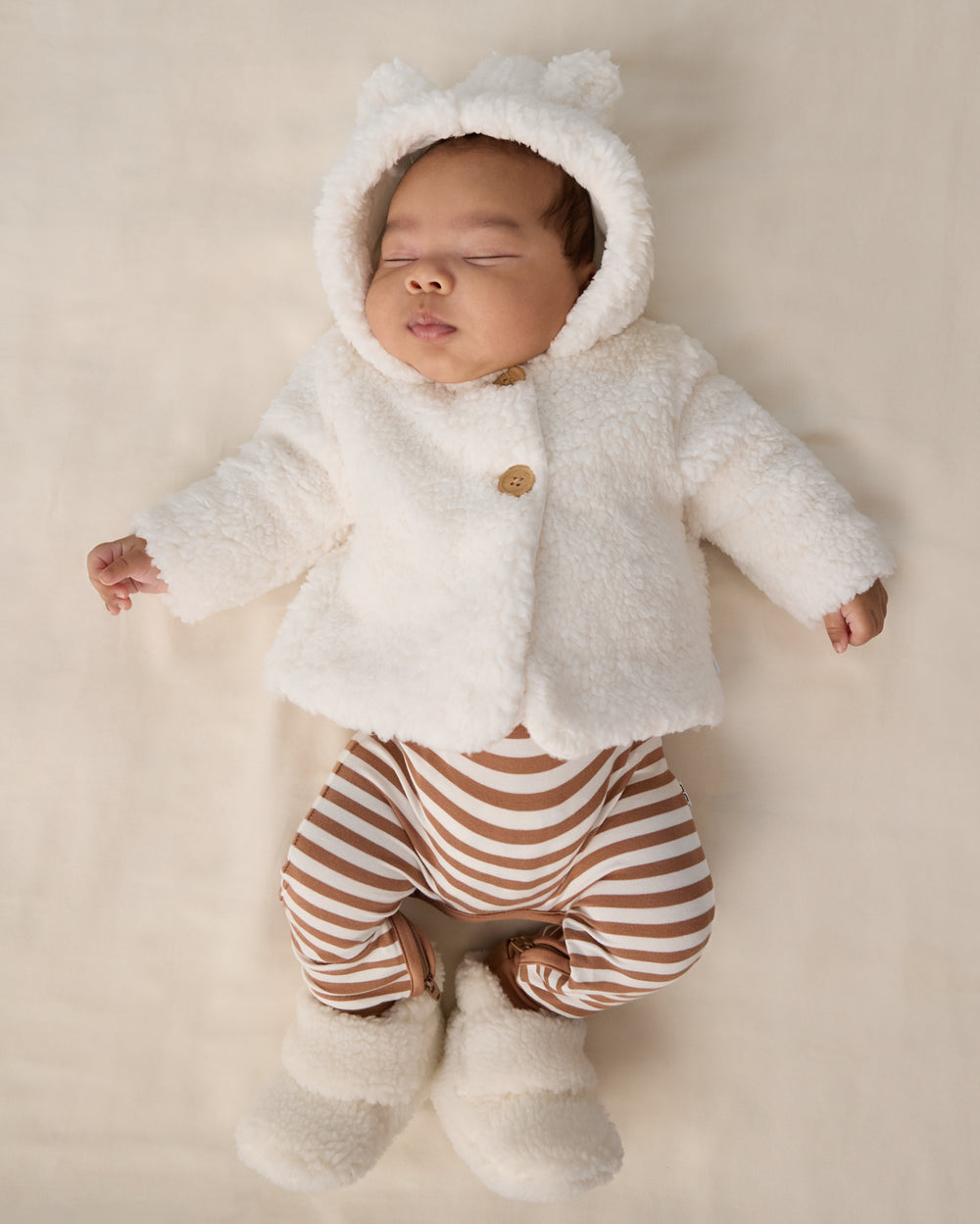 Newborn wearing the Chestnut Brown Stripe Crescent Zippy layered under a sherpa jacket