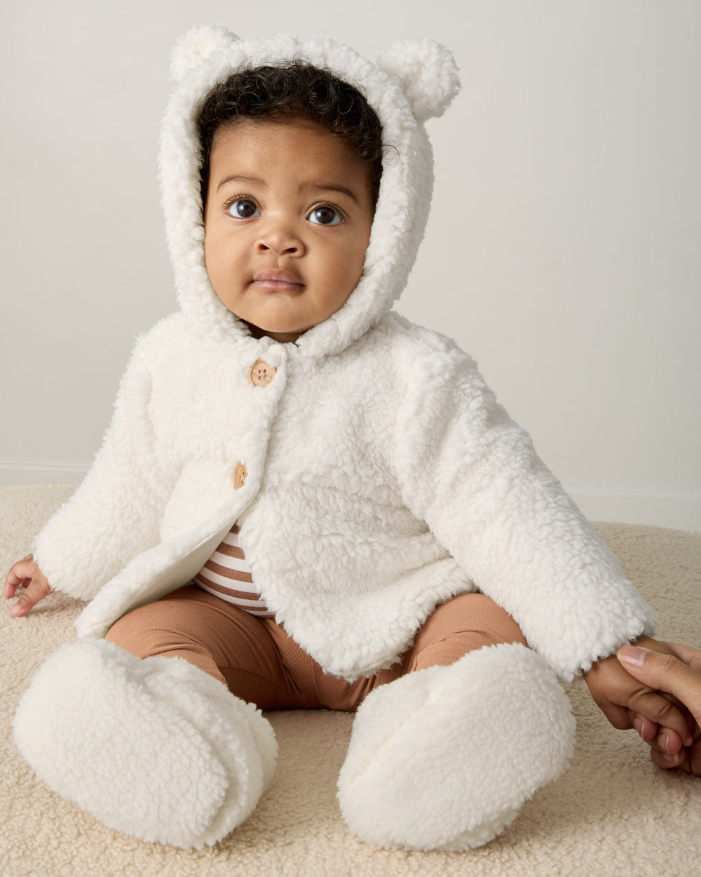 Sitting newborn wearing the Soft White Sherpa Baby Jacket and Soft White Sherpa Crossover Booties