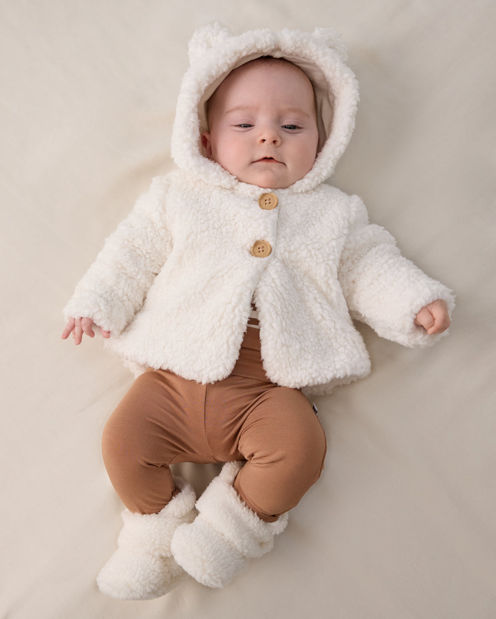 Aerial view of baby wearing the Soft White Sherpa Crossover Booties and Newborn Jacket