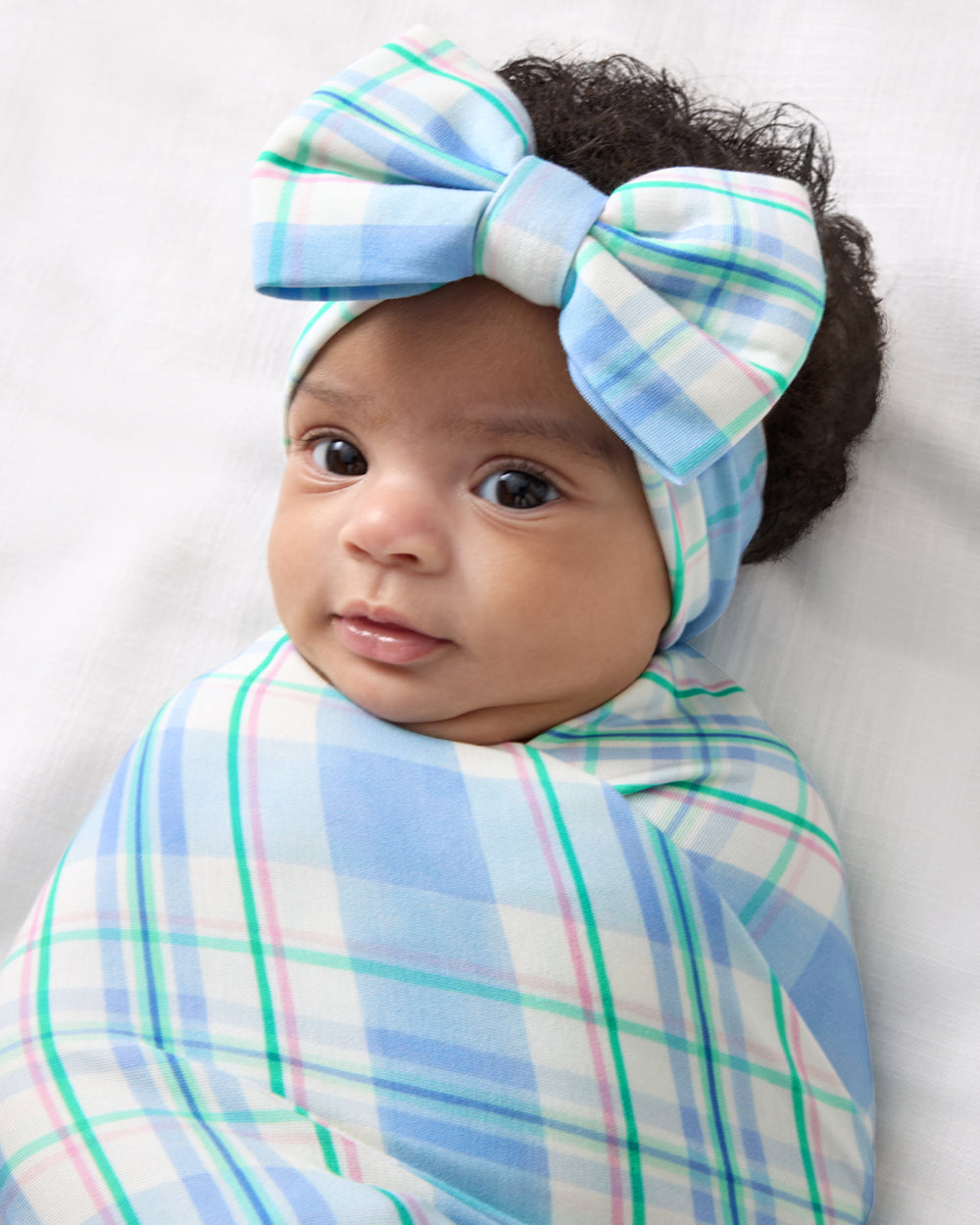 Baby swaddled in the Springtime Plaid Swaddle & Luxe Bow Headband Set