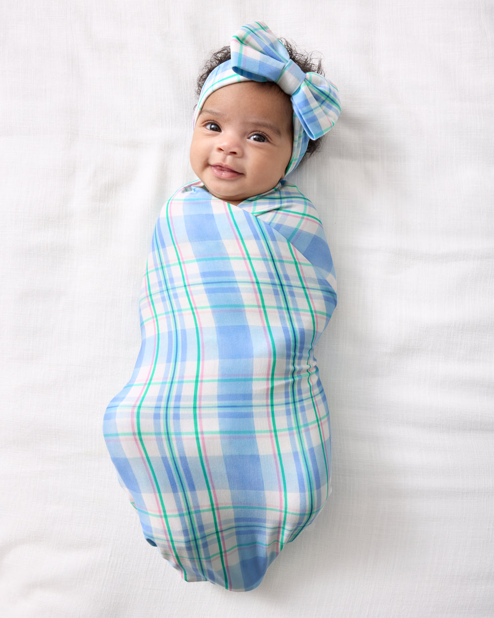 Aerial view of baby wearing the Springtime Plaid Swaddle & Luxe Bow Headband Set