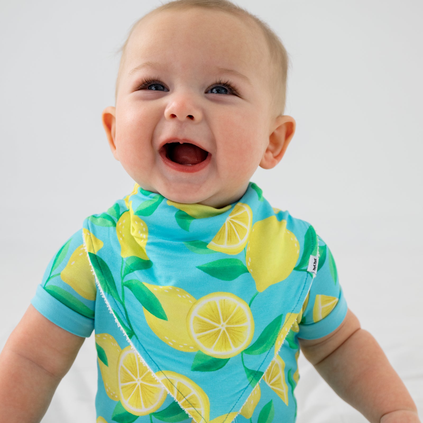 Smiling child wearing the Blue Sunny Citrus Bandana Bib