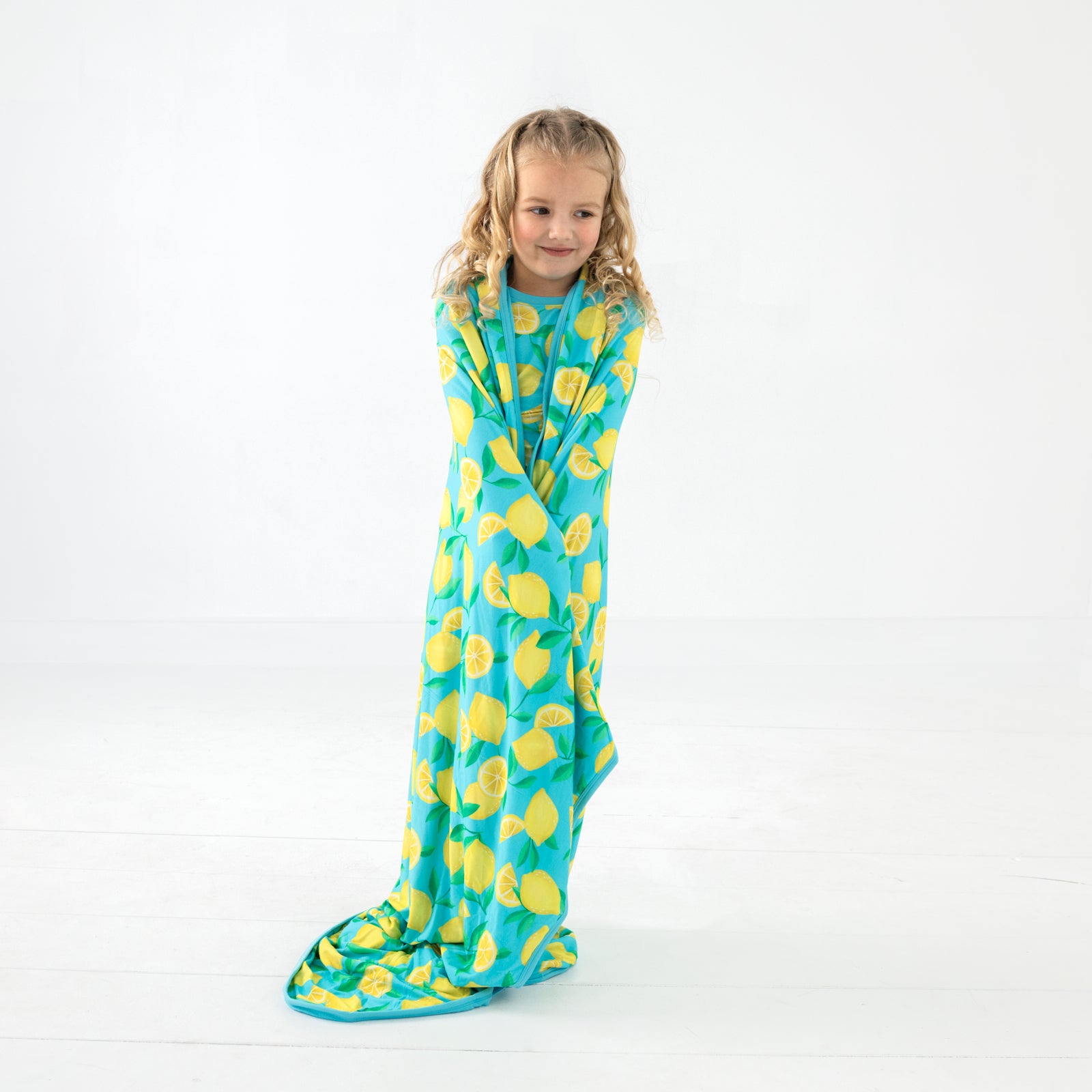 Standing child wrapped in the Blue Sunny Citrus Large Cloud Blanket®